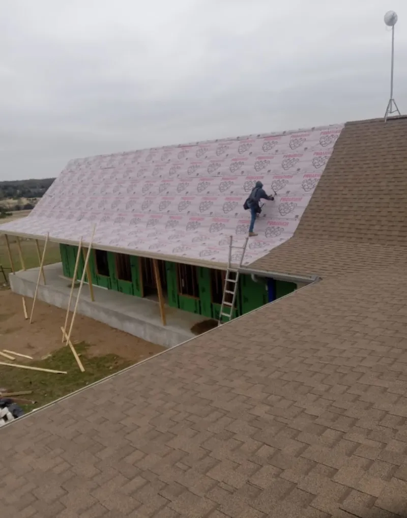Worker preparing underlayment for a metal roof installation in Camden
